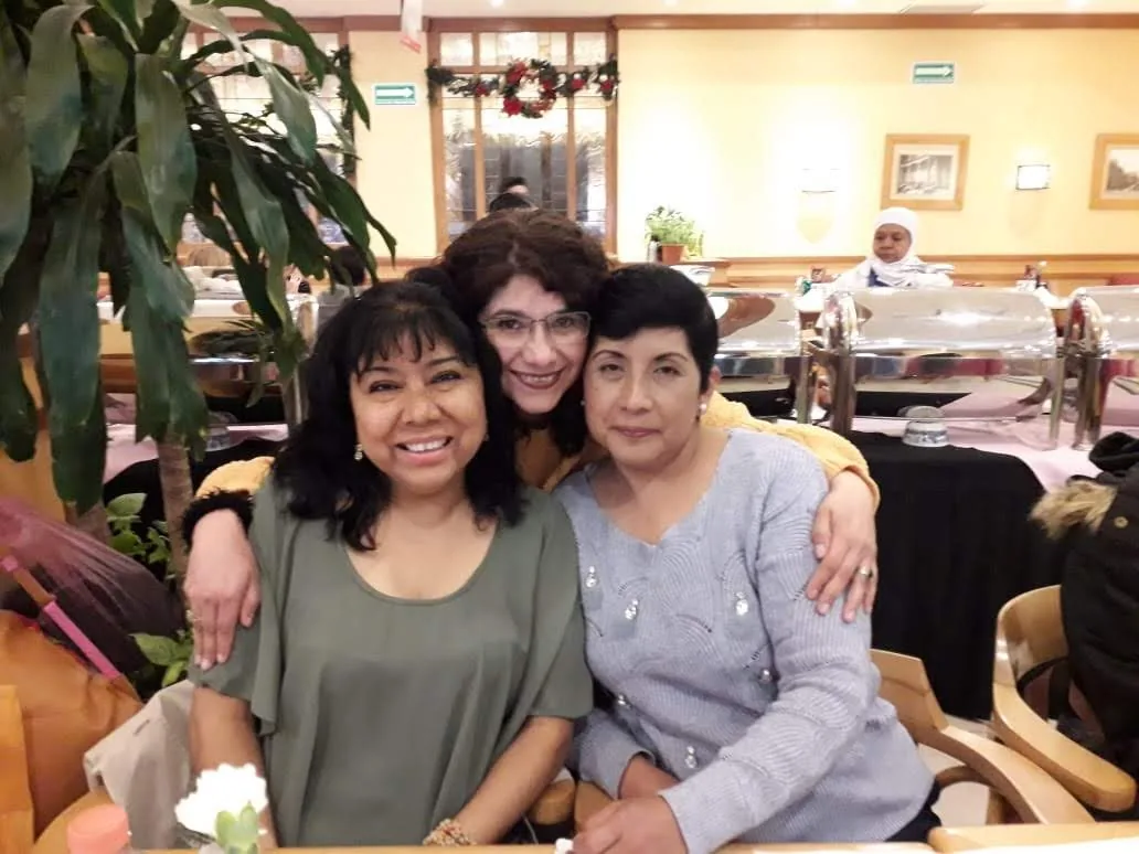 Tres integrantes de la fundación abrazadas en una reunión.