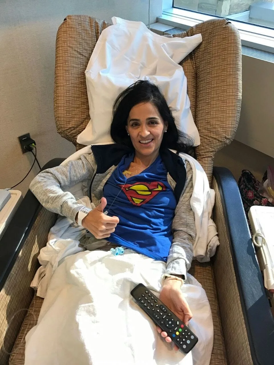 Paciente sonriendo con el pulgar arriba durante su tratamiento intravenoso.
